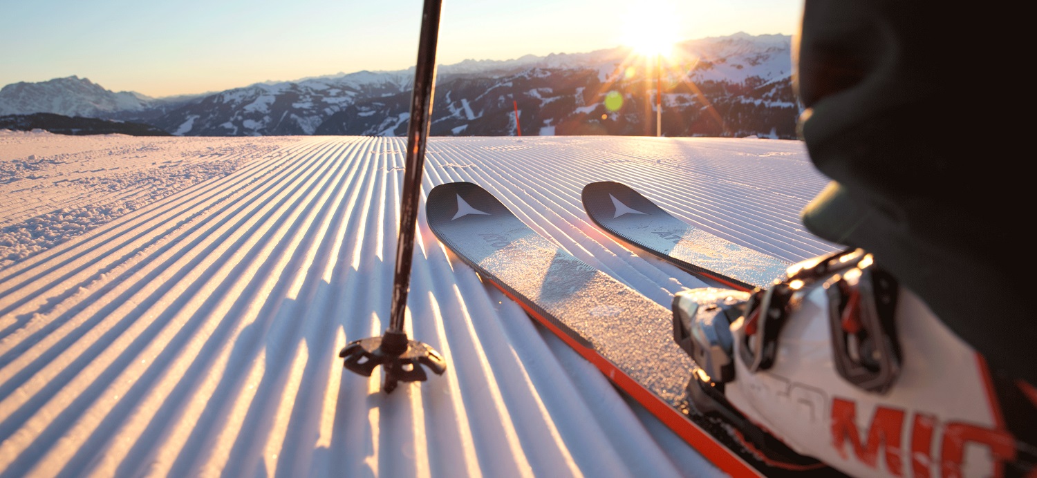 Close up of skis on a slopes with a background sunrise
